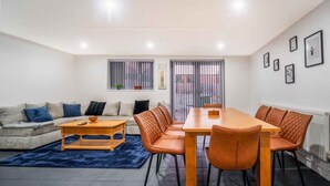 A modern living room with a sofa, coffee table, and dining table with chairs.
