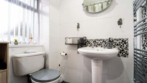 A bathroom with a toilet, sink, and decorative wall tiles.
