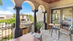 Un balcón con mesa y sillas, una planta en maceta y vistas del entorno.