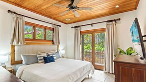 Un dormitorio con una cama grande, techo de madera y ventanas con cortinas.