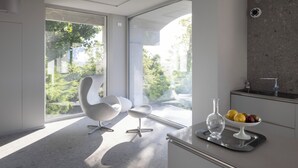 A modern kitchen with large windows, a white chair, and a fruit bowl on the counter. - Villa Itaca - Three Bedroom Villa, Sleeps 5 (Casorzo)