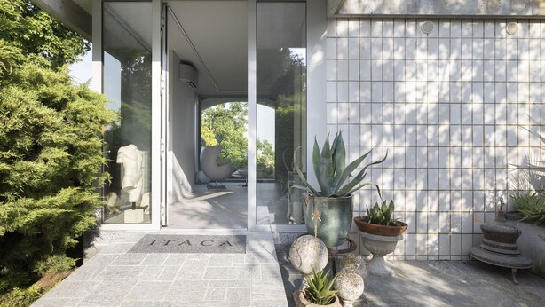 A modern building entrance with a glass door, potted plants, and a stone pathway leading to the door. - Villa Itaca - Three Bedroom Villa, Sleeps 5 (Casorzo)