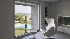 A modern room with a large window, a white chair, and a framed picture on the wall. - Villa Itaca - Three Bedroom Villa, Sleeps 5 (Casorzo)