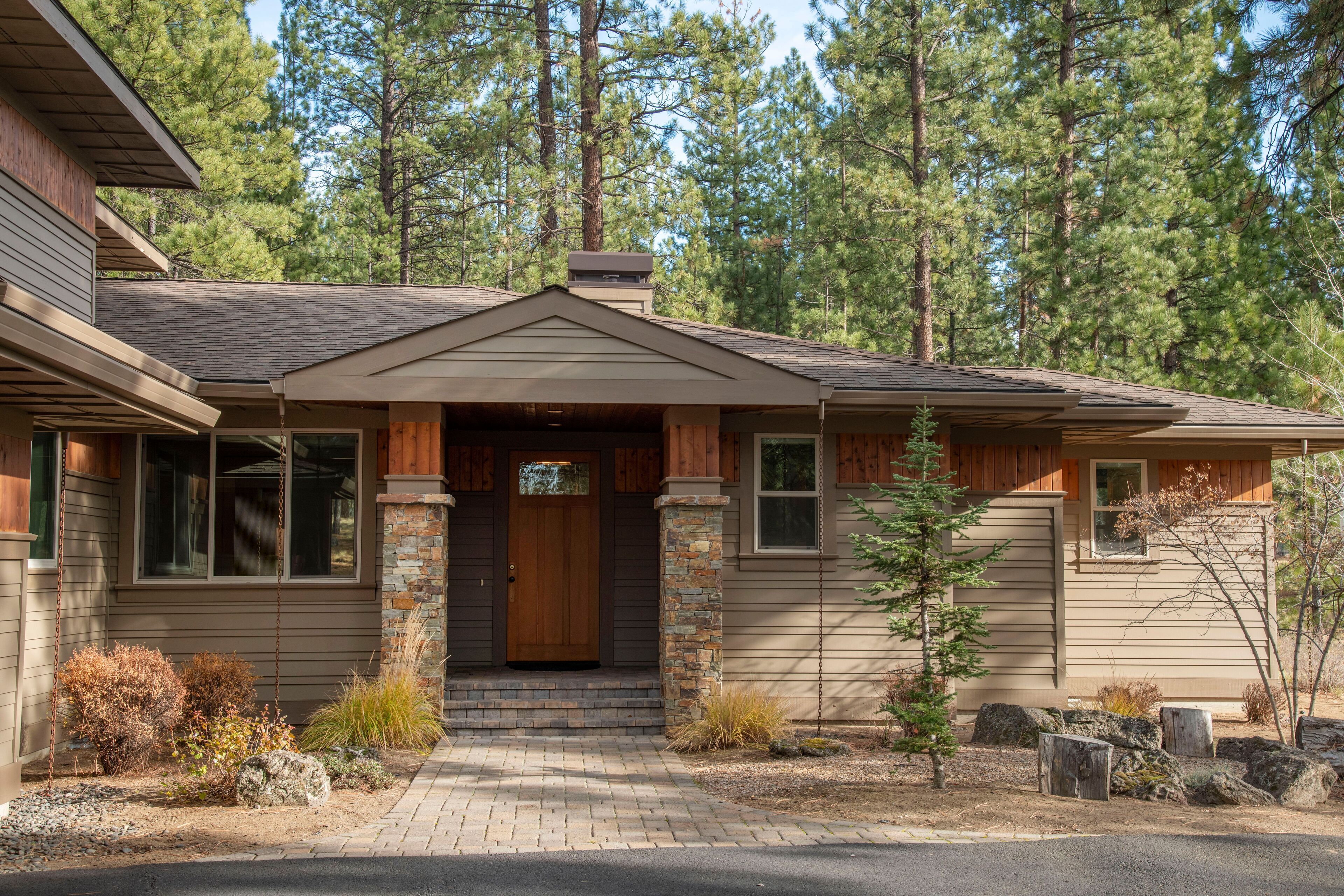 A two-story house with a front porch, stone pillars, and a wooden door.