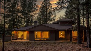 Une cabane moderne dotée de grandes fenêtres, d’un porche abrité et d’une cheminée.