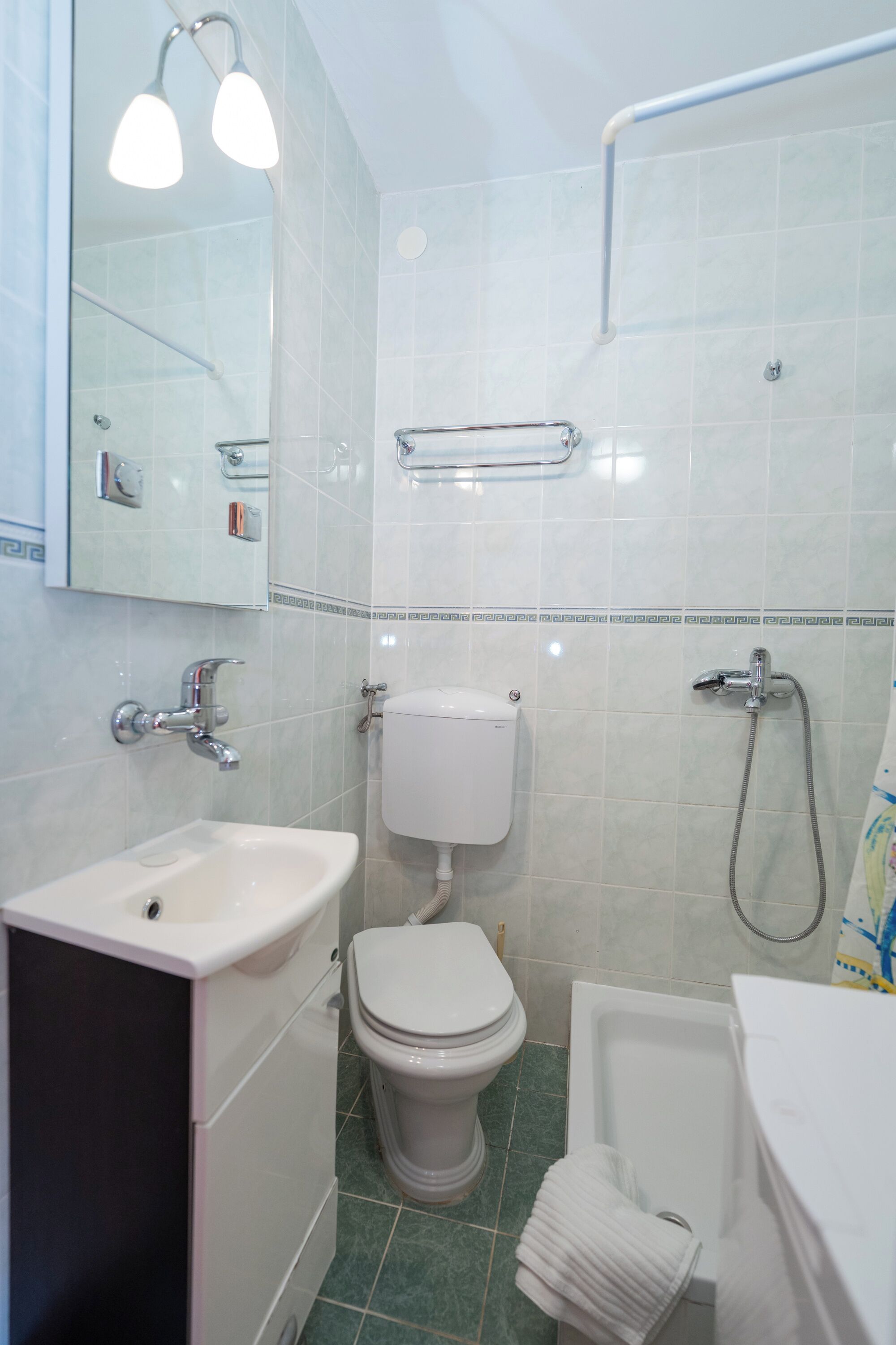 Ein Badezimmer mit Waschbecken, Toilette, Dusche und Handtuchhalter.