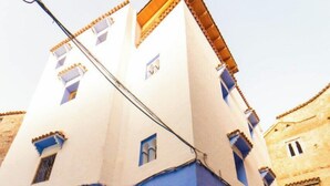 Ein Gebäude mit blauer Fassade, einer Holztür und einem Ziegeldach.