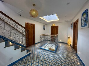A hallway with a patterned floor, a staircase with a metal railing, and a skylight. - Diyar Marhaba (Chefchaouen)