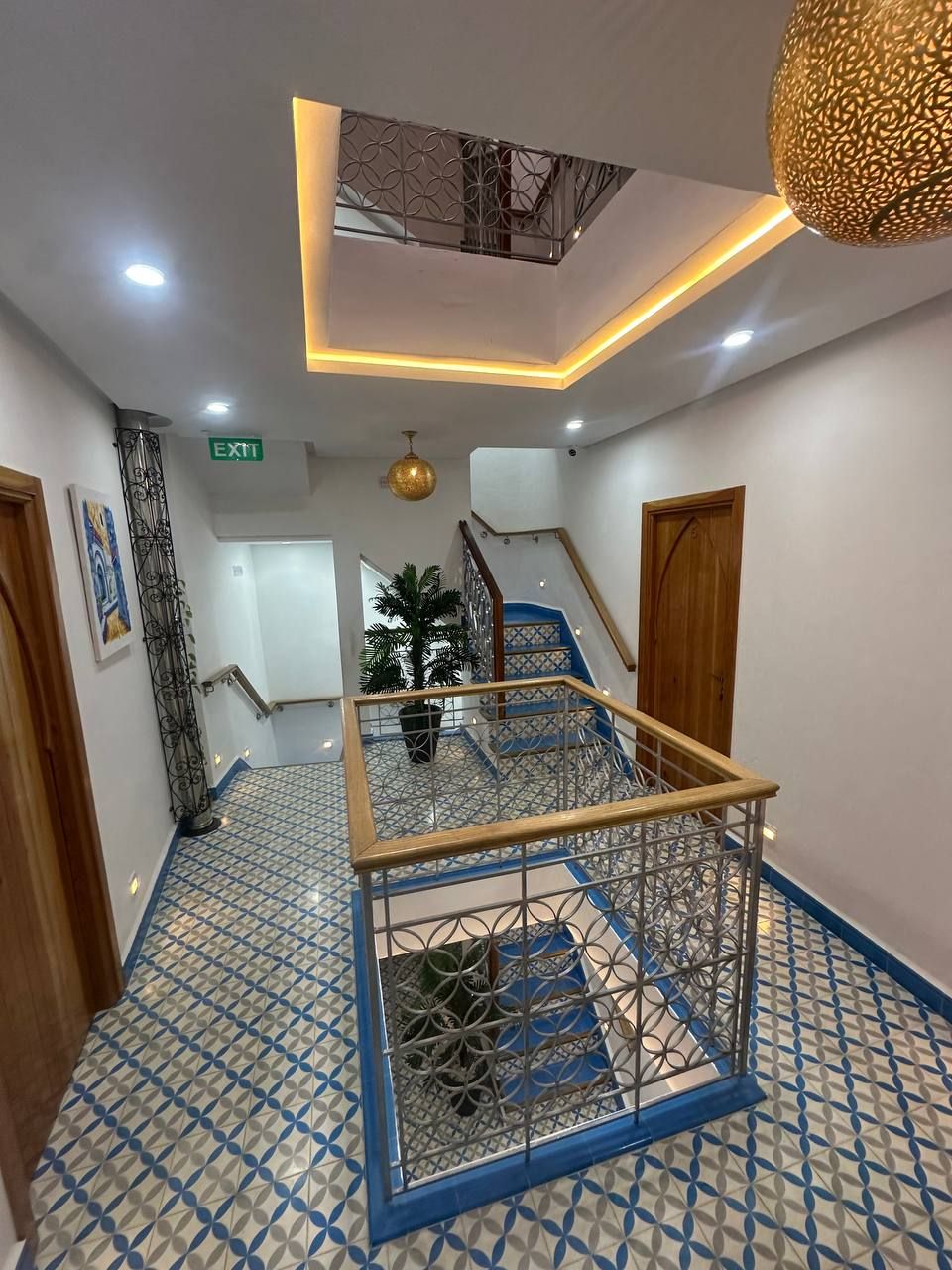 Un'accogliente hall d'albergo con una scala, un soffitto decorato e pavimento a motivi.