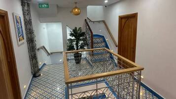 Un vestíbulo de hotel con una escalera, un techo decorativo y un suelo estampado.