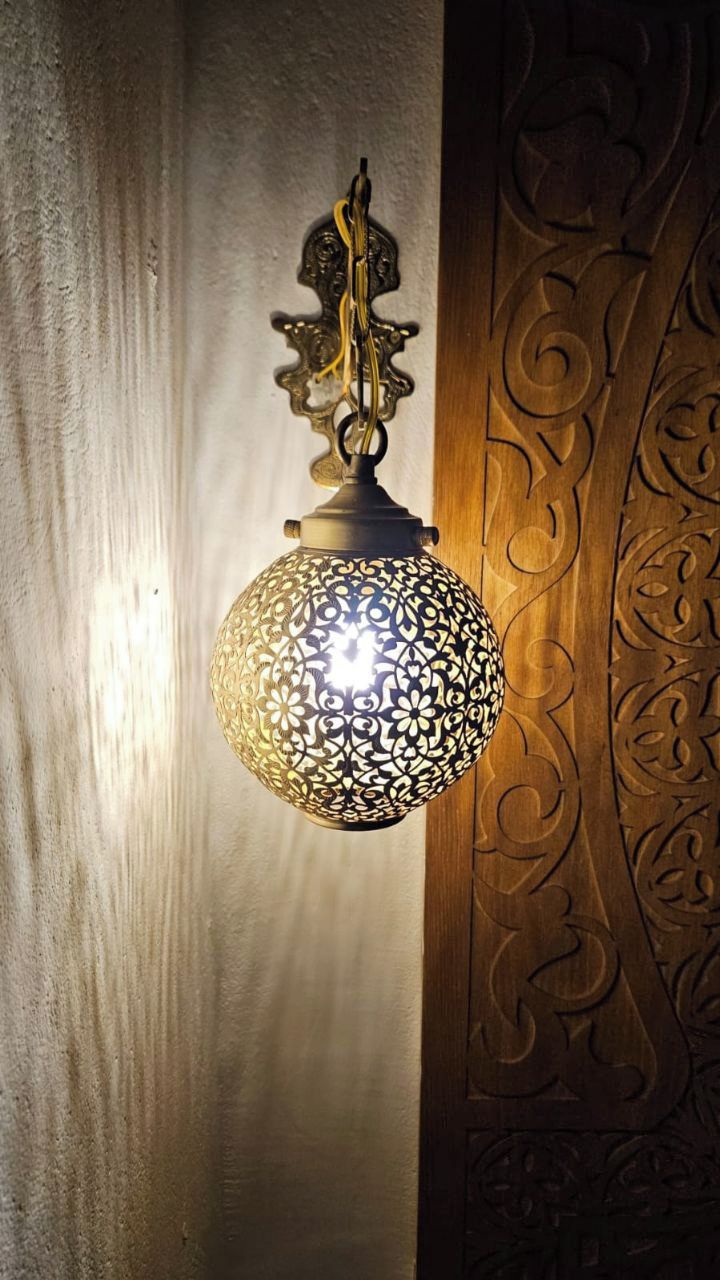 A wall-mounted light fixture with intricate patterns and a hanging chain.