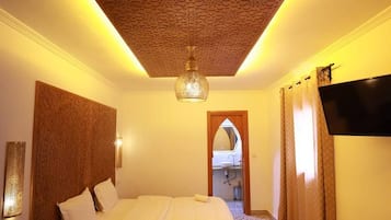 Una habitación de hotel con una cama, un escritorio, un televisor y un piso con diseño.