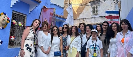 Un grupo de personas posando en una calle estrecha con edificios pintados de azul y blanco.