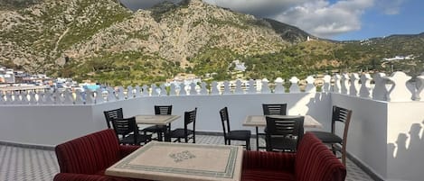 Una terraza al aire libre con mesas y sillas, con vistas a un paisaje montañoso.