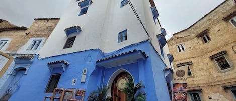 Un edificio con fachada azul, puerta de madera y un letrero que dice "MARHABA".