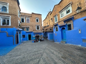 A narrow street with buildings painted in blue and beige, leading to a small shop at the end. - Diyar Marhaba (Chefchaouen)
