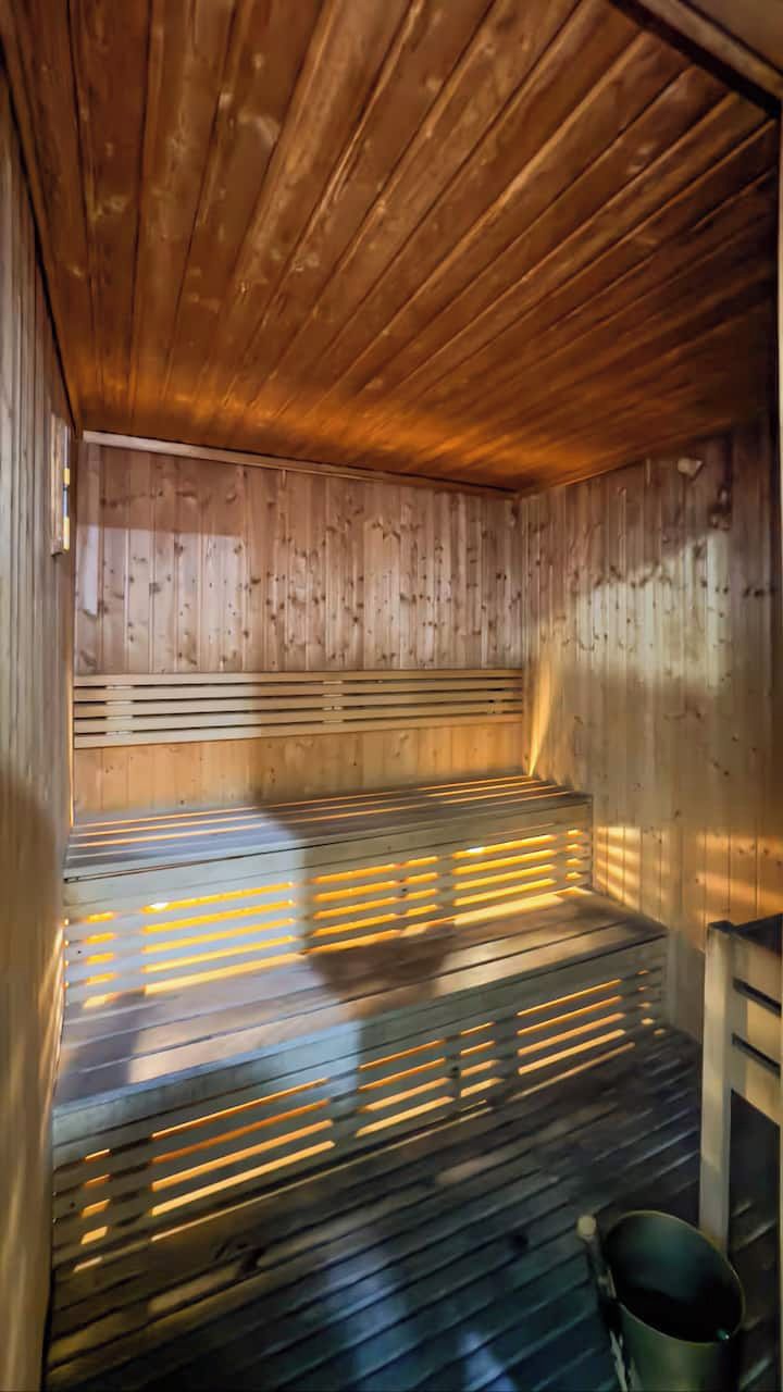 En sauna med træbænke og bræddegulv, en balje og et træloft.
