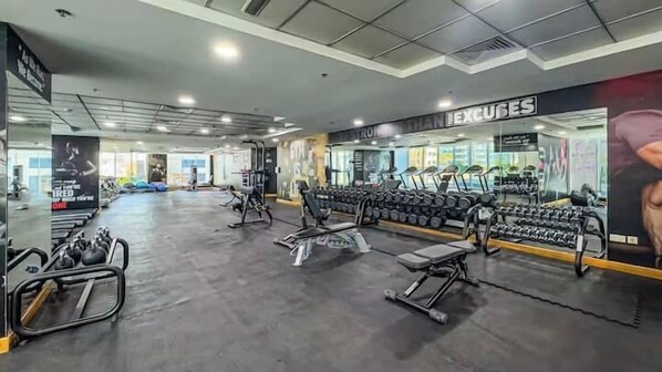 Une salle de sport équipée de bancs de musculation, d’haltères et d’appareils d’exercice.