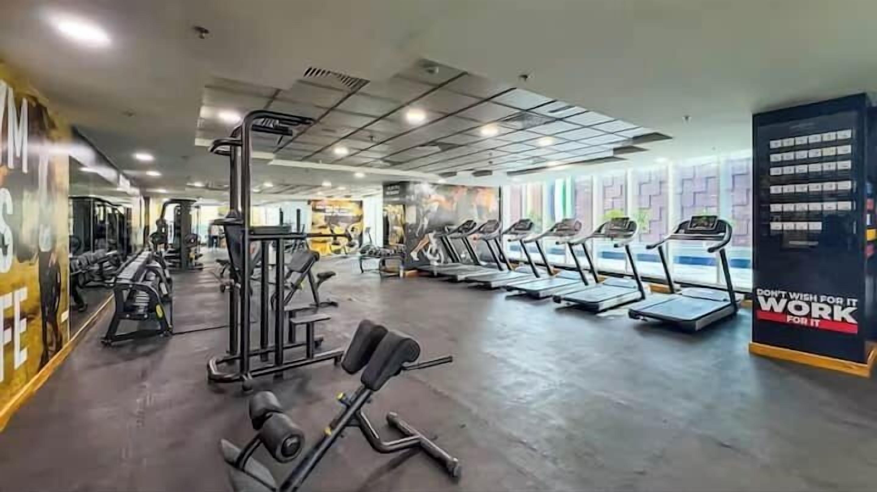A gym with treadmills, weight machines, and a motivational poster.
