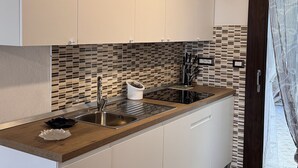 A modern kitchen with white cabinets, a wooden countertop, a sink, and a hanging light fixture.
