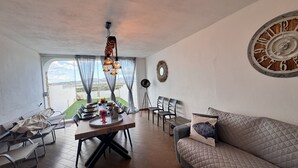 A dining area with a table set for four, a sofa, and a large wall clock.