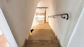 A staircase with a handrail, a patterned curtain, and a wall-mounted light fixture.