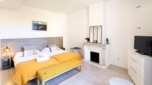 A modern bedroom with a bed, bedside table, lamp, fireplace, and TV. - Lovely and Modern 1 Bedroom City Centre Cannes (Cannes)