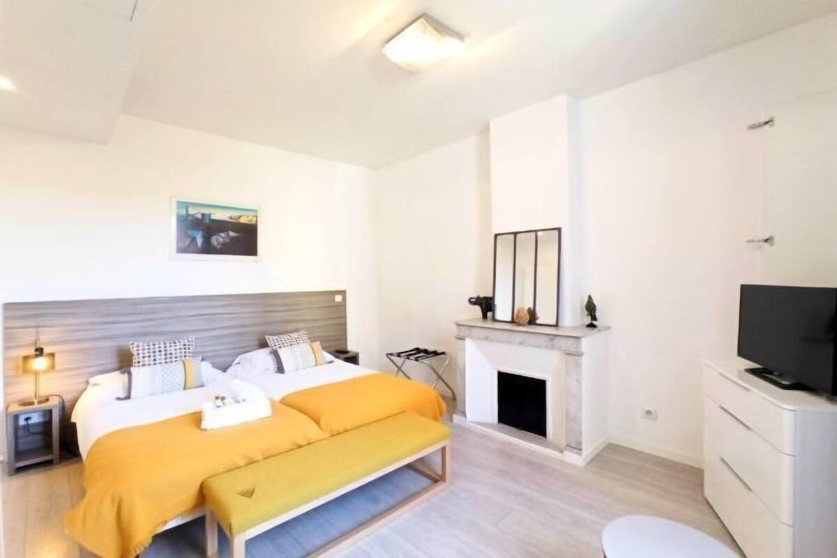 A modern bedroom with a bed, bedside table, lamp, fireplace, and TV.