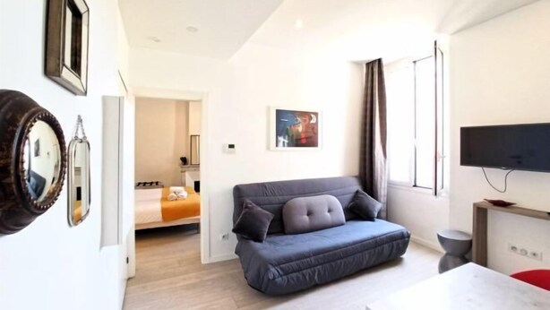 A modern living room with a sofa, a flat-screen TV, and a dining table. - Lovely and Modern 1 Bedroom City Centre Cannes (Cannes)