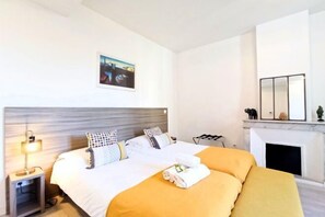 Ein Hotelzimmer mit einem Bett, einem Nachttisch, einer Lampe, einem Kamin und einem gerahmten Bild an der Wand.