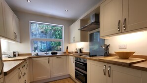 A modern kitchen with white cabinets, a wooden countertop, a large window, and a built-in oven. - Lingmell Fell View, Chapel Stile (Chapel Stile)