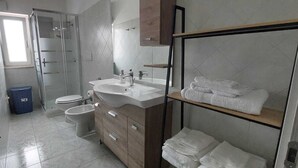 Un baño moderno con cabina de ducha de vidrio, lavabo, inodoro y toallero.