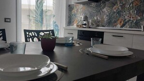 Un comedor con una mesa preparada para cuatro personas, una planta en maceta y un mural temático tropical.