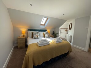 A bedroom with a bed, bedside tables, a skylight, a radiator, and a wall-mounted drying rack. - Forth, seaside 3 bed apartment, stunning views, convenient, central location , (Pittenweem)