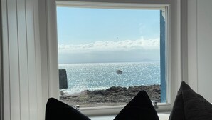 A room with a view of the sea through a window, a chair, and two pillows. - Forth, seaside 3 bed apartment, stunning views, convenient, central location , (Pittenweem)