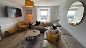 A modern living room with a sofa, armchair, coffee table, and a TV mounted on the wall. - Forth, seaside 3 bed apartment, stunning views, convenient, central location , (Pittenweem)