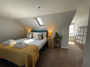 A bedroom with a bed, bedside tables, a lamp, a potted plant, and a skylight.