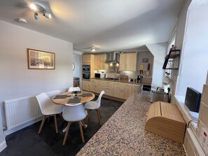A compact kitchen with a dining area, featuring a round table, chairs, and a built-in oven. - Forth, seaside 3 bed apartment, stunning views, convenient, central location , (Pittenweem)