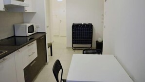Une cuisine compacte équipée d’un four à micro-ondes, d’un évier et d’une table à manger avec des chaises.