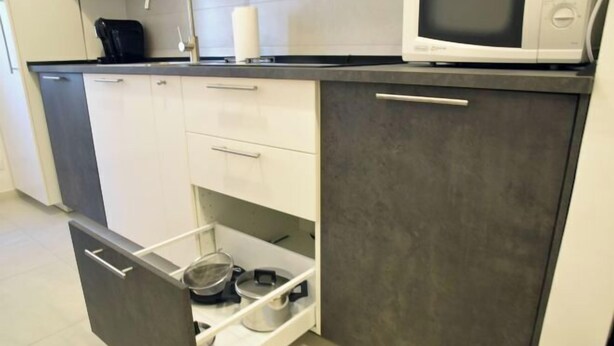 Une cuisine compacte équipée d’un four à micro-ondes, d’une bouilloire et d’un petit évier.