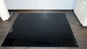 Un îlot de cuisine rectangulaire de couleur noire, doté d’un plan de travail et d’un évier.