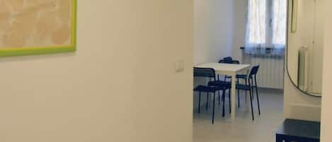 Een eethoek met een tafel, stoelen, een spiegel en een raam met gordijnen.
