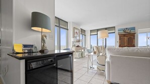 A modern kitchen with a dishwasher, a dining area with a table and chairs, and a living room with a sofa.