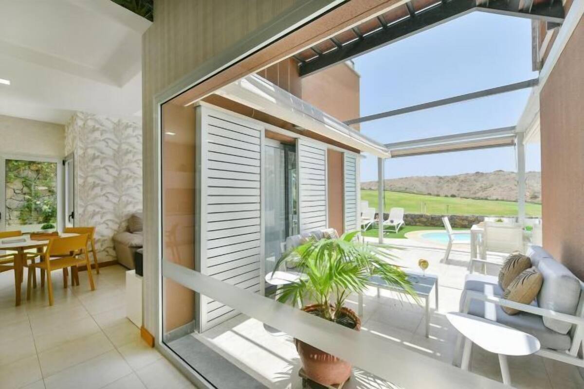 Un intérieur moderne comprenant un coin repas, un balcon avec mobilier d’extérieur et une vue sur une piscine.