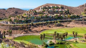 A resort with multiple buildings, a golf course, and a large body of water. - Vista Golf 10 Salobre by VillaGranCanaria (Comarca Sur)