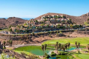 A resort with multiple buildings, a golf course, and a body of water. - Vista Golf 10 Salobre by VillaGranCanaria (Comarca Sur)