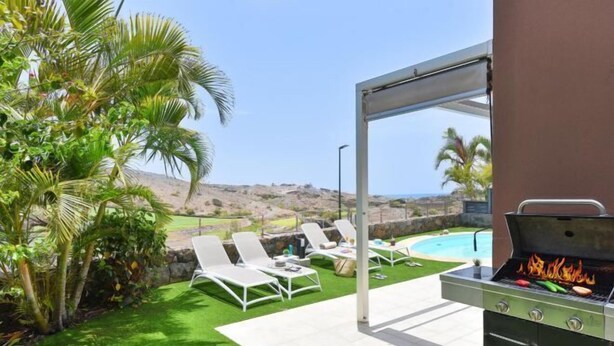 An outdoor patio with a grill, lounge chairs, and a view of the landscape. - Vista Golf 10 Salobre by VillaGranCanaria (Comarca Sur)