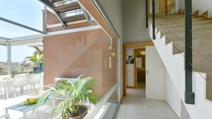 A modern interior with a staircase, a dining area with outdoor seating, and a potted plant. - Vista Golf 10 Salobre by VillaGranCanaria (Comarca Sur)
