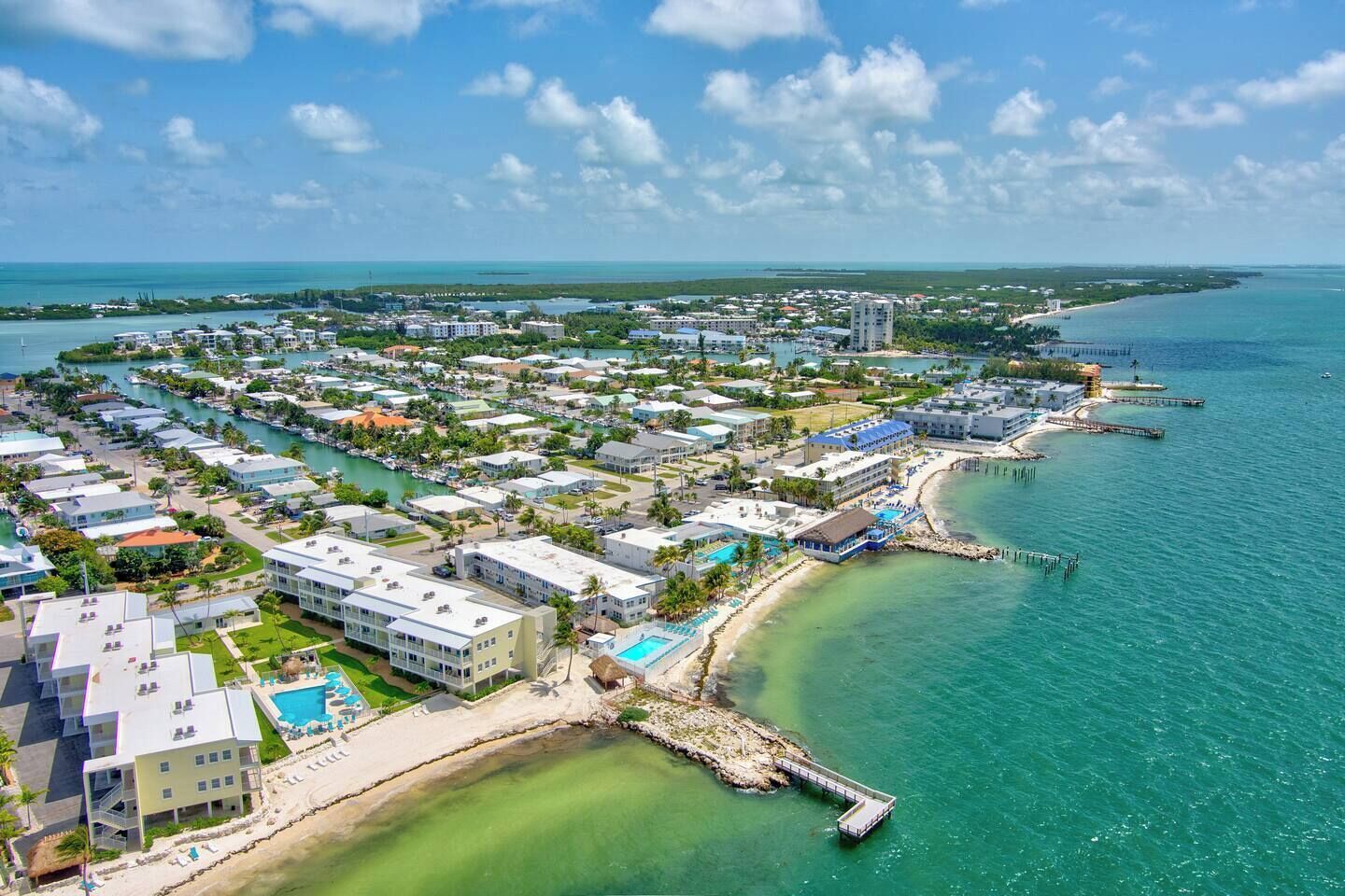 An aerial view of a coastal resort with multiple buildings, a beach, and a pier.