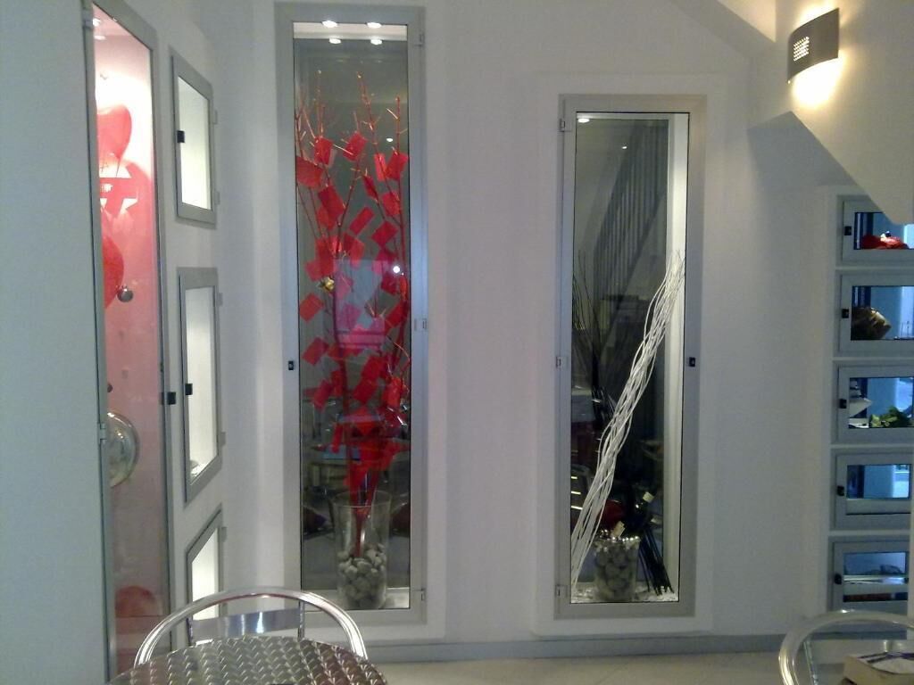 Un pasillo con puerta de cristal, una silla de metal y una escalera.